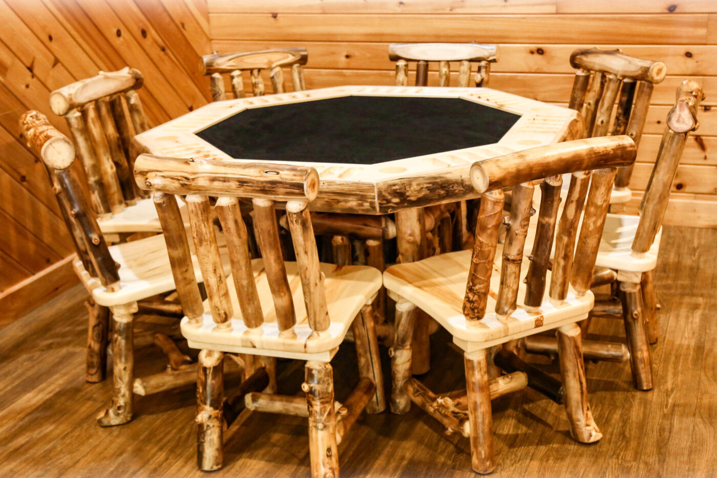 Handcrafted Rocky Mountain Aspen rustic dining set with a hexagonal table featuring a black inlay top, surrounded by eight handcrafted aspen wood chairs